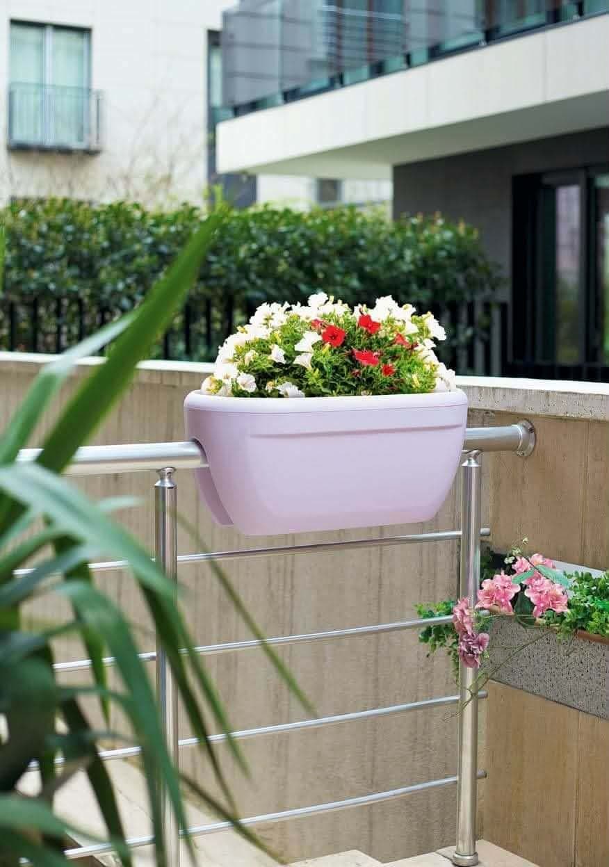 Pot Rubi Plast accroché au garde-corps d'un balcon fleuri